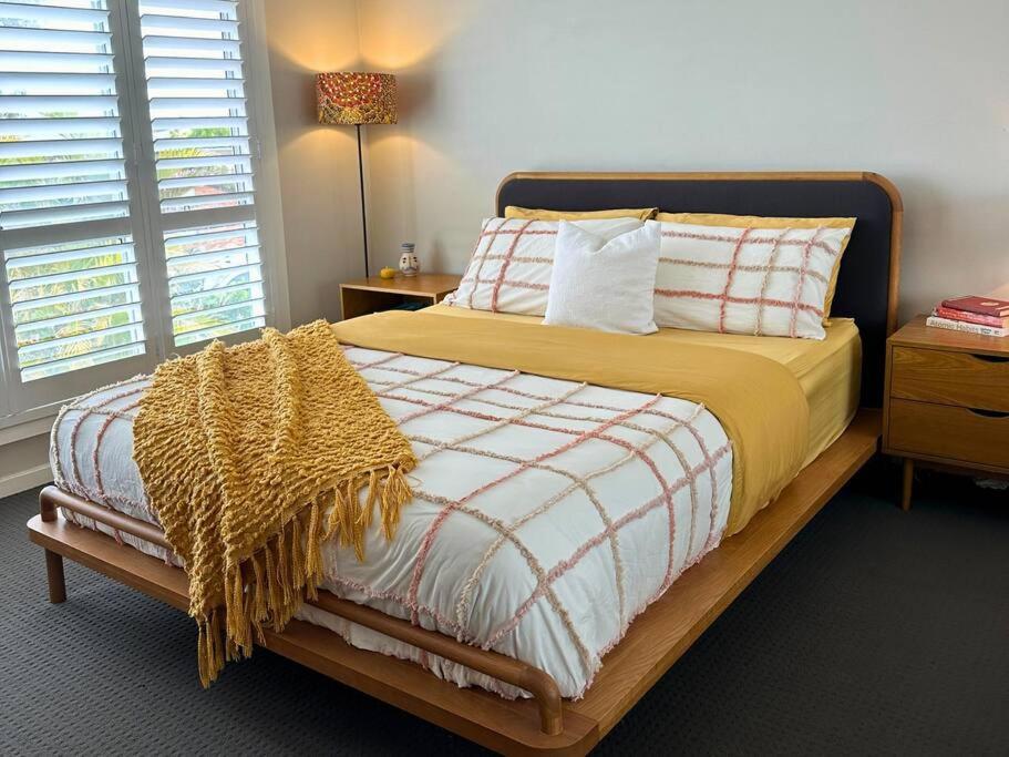 une chambre avec un lit avec une couverture dessus dans l'établissement Casa Dis Family Friendly 350m walk to beach, à Caves Beach