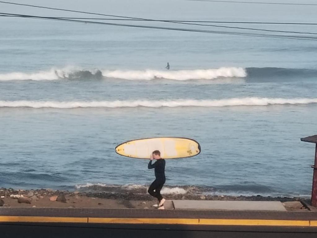 a person carrying a surfboard on the beach at Departamento con HERMOSA VISTA AL PACÍFICO in Huanchaco