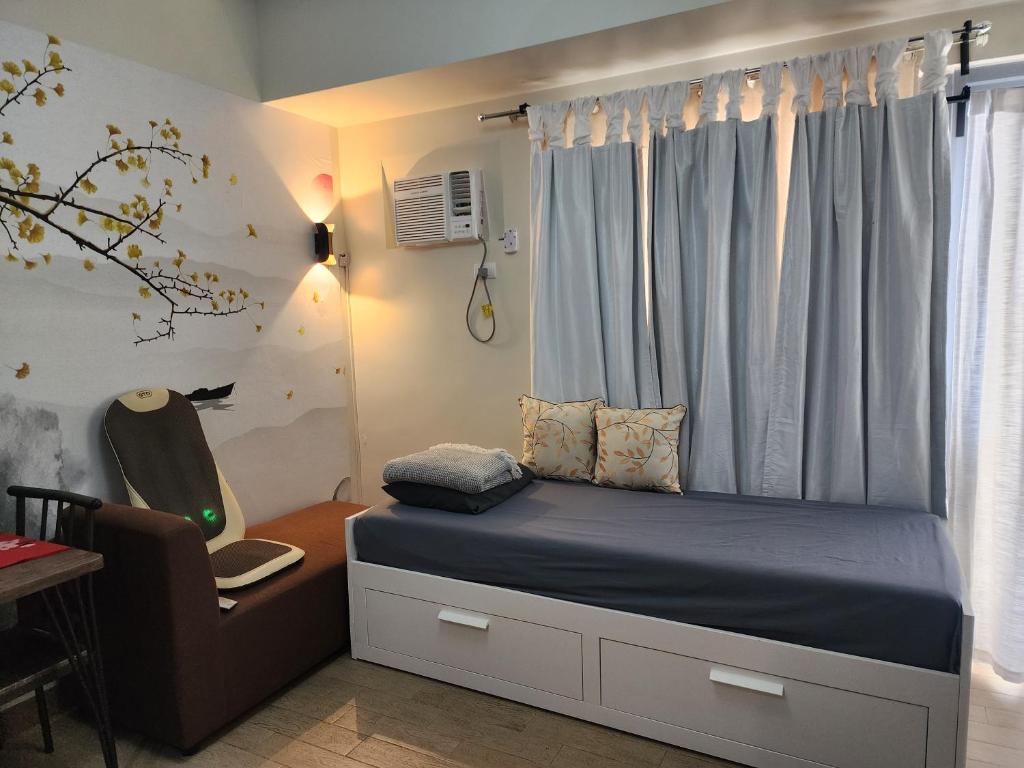 a bedroom with a bed with a chair and a window at DG CONDOTEL @MANHATTAN PLAZA T2 STUDIO WITH BALCONY , 50 INCH TV AND UNLI WIFI @Araneta Cubao Quezon City Philippines in Manila