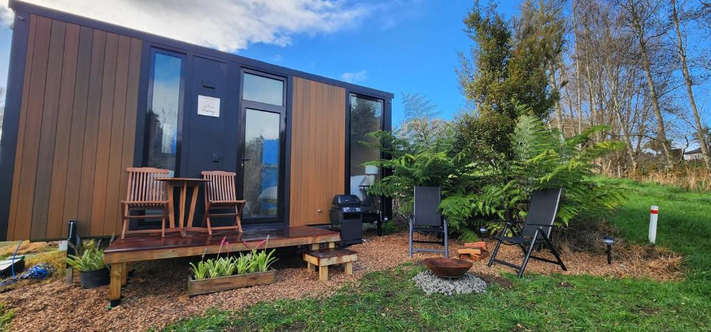 a tiny house with a table and chairs in a yard at Cozy Cabin2 with outdoor Bath at Dairy Flat Farm in Waitoki
