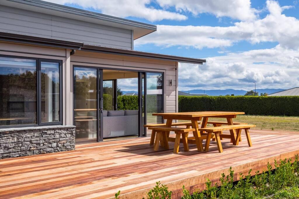 a wooden deck with a picnic table in front of a house at Stonehenge Retreat in Martinborough