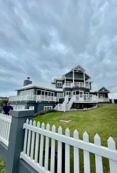 a white fence in front of a large house at SandDollar - Self Catering Seaside Getaway in Cape St Francis