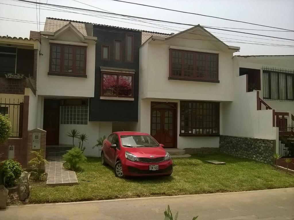 una macchina rossa parcheggiata di fronte a una casa di Familia Tome a Chaclacayo