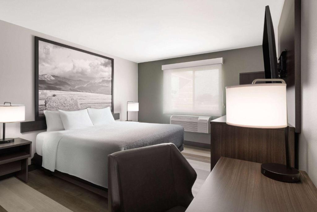 a hotel room with a bed and a chair at Super 8 by Wyndham Big Timber in Big Timber