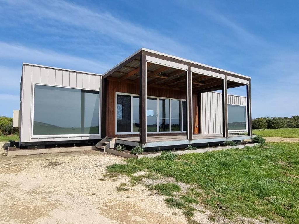 NarrawongOcean View Retreat的现代房屋,在田野上设有玻璃窗