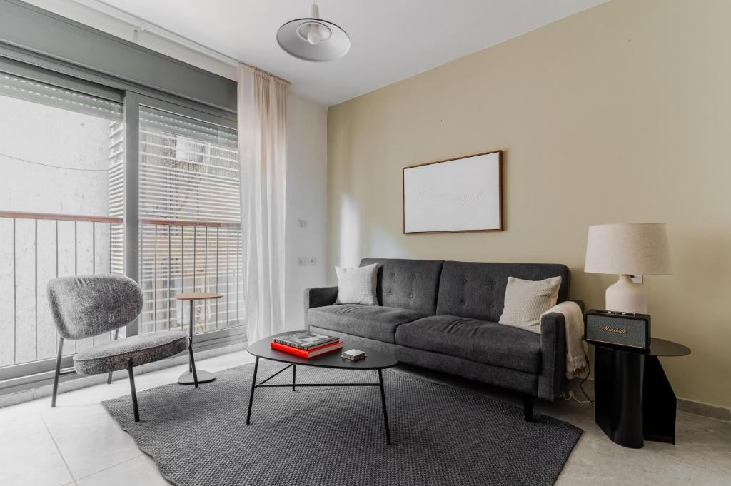 a living room with a couch and a table at Blueground Florentine, City view in Tel Aviv