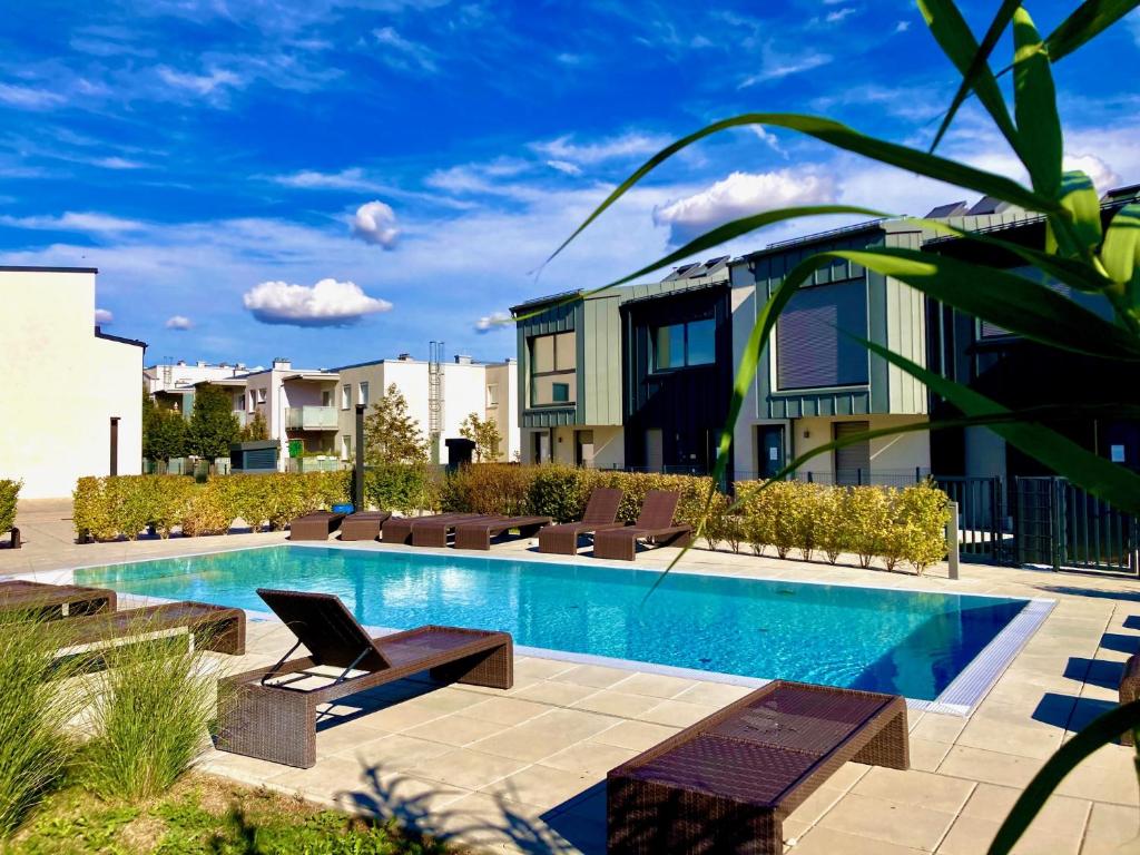 a swimming pool with lounge chairs next to a building at Apartments C'EST LA SEA - Whirlpool-Suite oder Dachterrassen-Suite - Pets welcome in Neusiedl am See