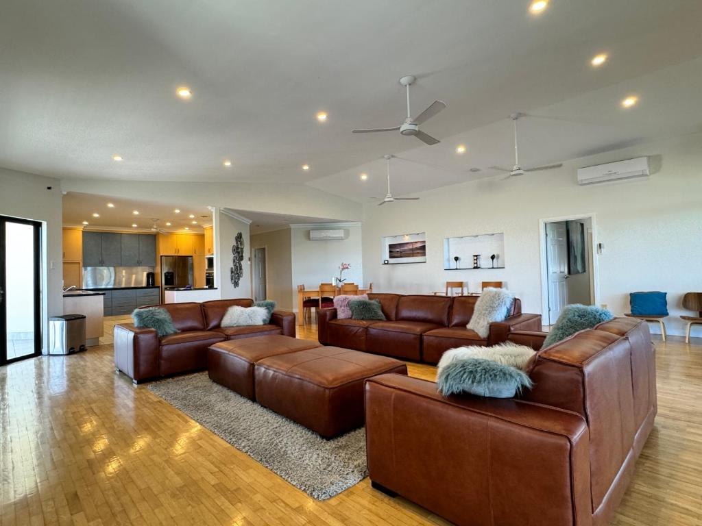 a living room with brown leather furniture and a kitchen at Townsville Apartments on The Strand - Penthouse in Townsville