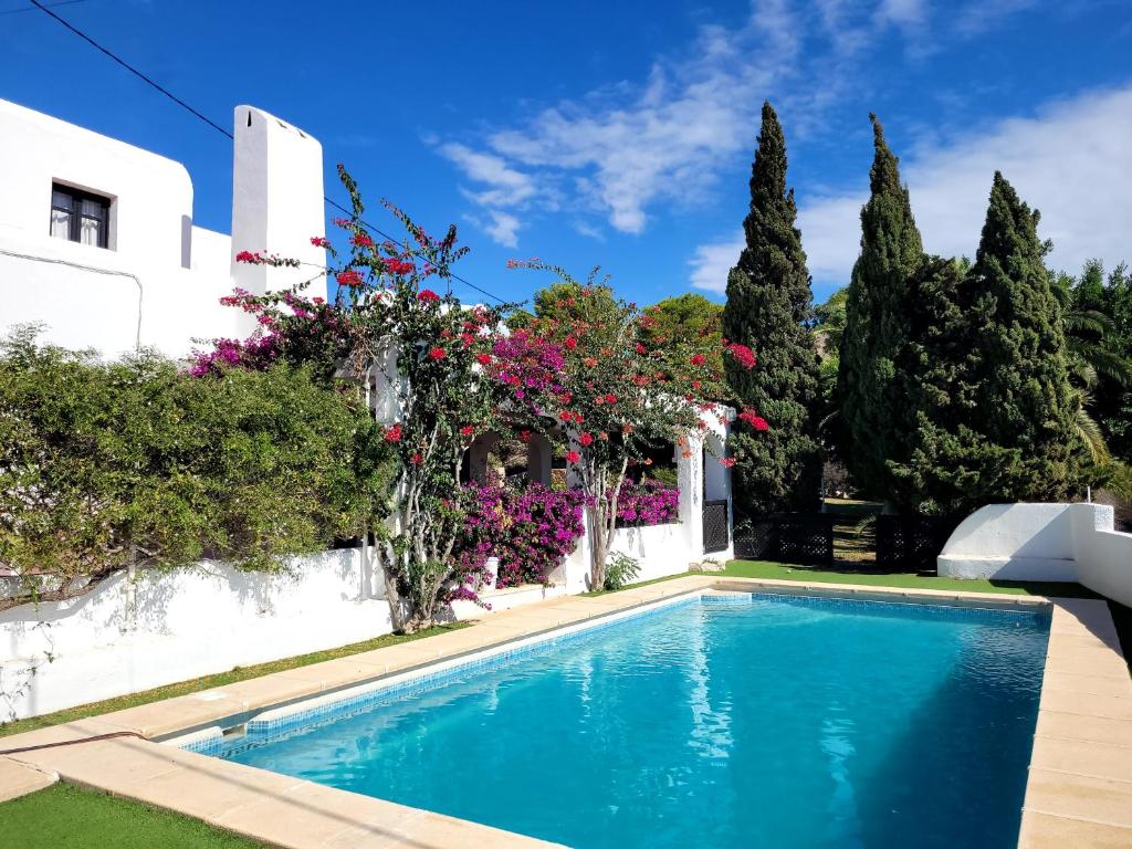 a swimming pool in front of a house with flowers at Casa La Cúpula in Agua Amarga