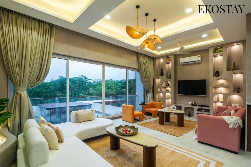 a living room filled with furniture and a large window at EKOSTAY - Casa Enzo 7BHK -Theatre Room Private Swimming Pool and Indoor Games in Lonavala