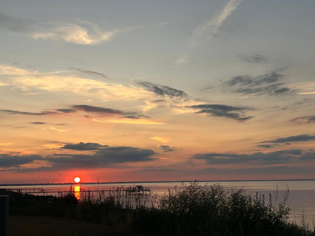a sunset over a body of water with a lighthouse at Stevns Camp in Strøby