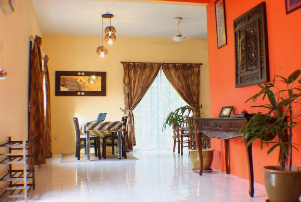 una sala da pranzo con pareti arancioni, tavolo e sedie di Balinese Villa at Seri Kembangan12 to15 pax a Seri Kembangan