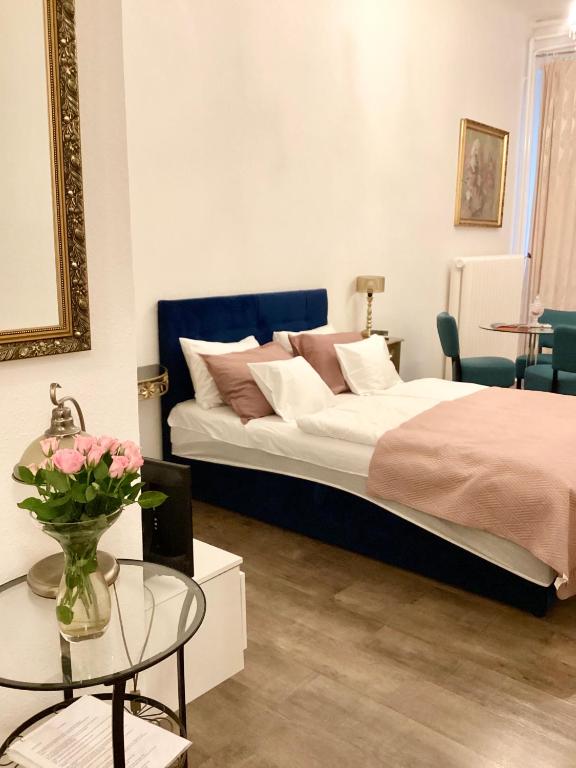 a bedroom with a bed and a table with a vase of flowers at Hungaricum Budapest in Budapest