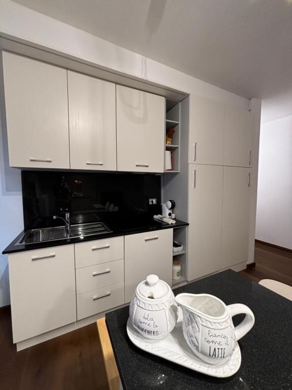Una cocina con gabinetes blancos y dos teteras sobre una mesa. en Dimora Rosé, en Alba