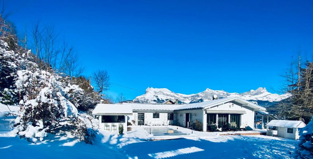 une maison avec des montagnes enneigées en arrière-plan dans l'établissement Chalet Soleil Blanc au pied des pistes, à Saint-Gervais-les-Bains