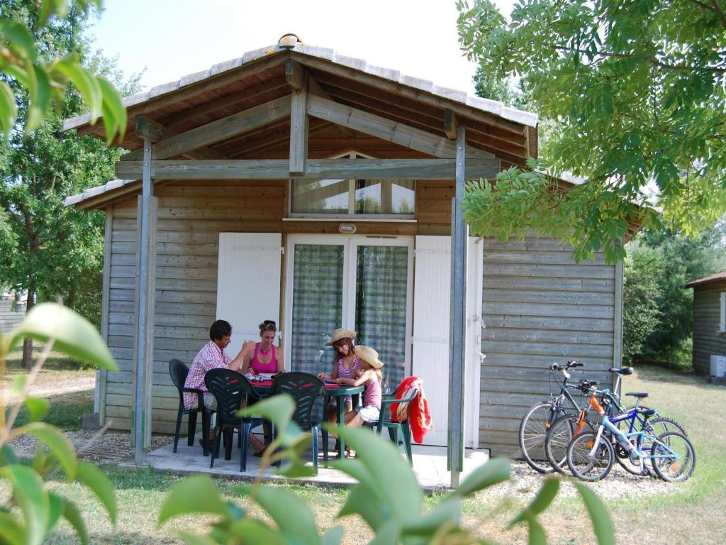 trois femmes assises à une table devant une cabine dans l'établissement Chalet in France with Garden Terrace, à Castelmoron-sur-Lot