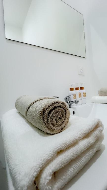 a white bathroom with towels on a sink at Le Petit Cocon - Pause douceur in Cambrai