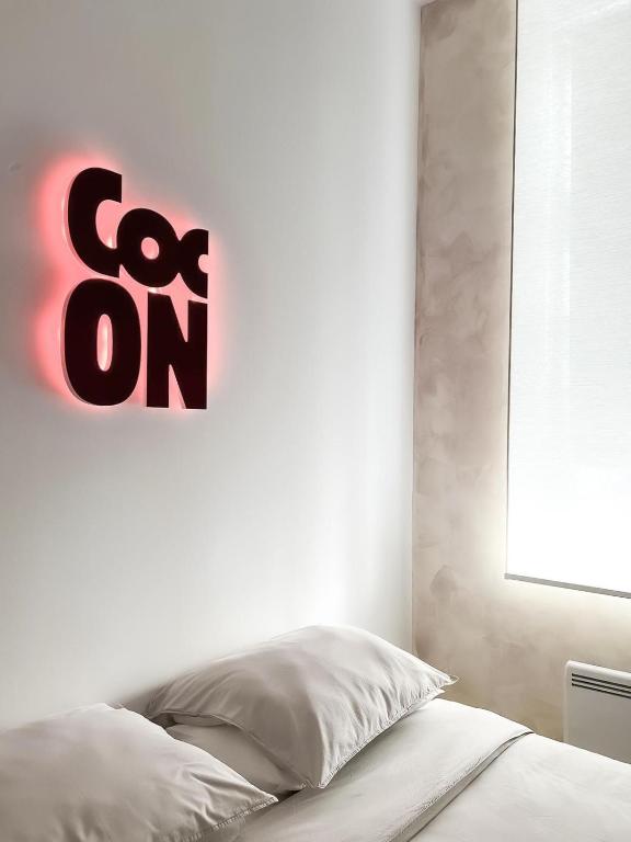 a bedroom with a bed with a sign on the wall at Le Petit Cocon - Pause douceur in Cambrai