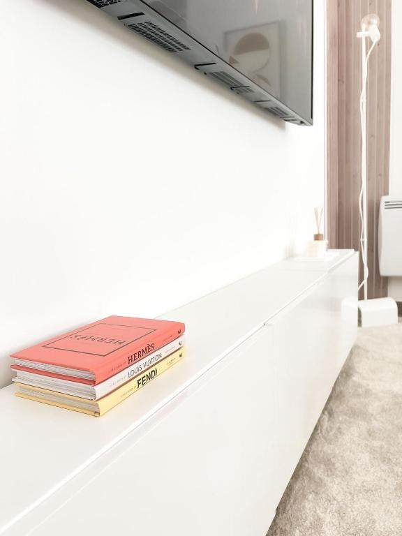 a stack of books sitting on a white shelf at Le Petit Cocon - Pause douceur in Cambrai