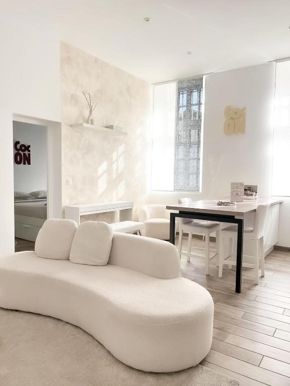 a white living room with a couch and a table at Le Petit Cocon - Pause douceur in Cambrai