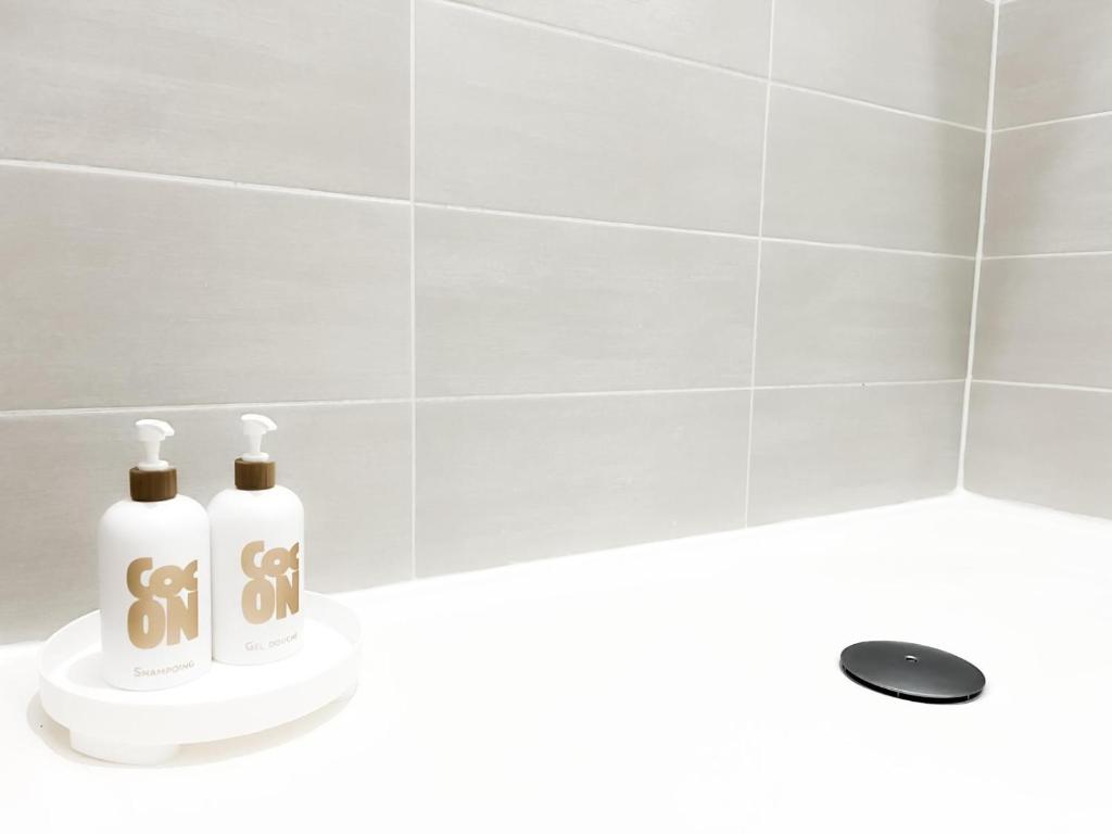 two bottles of soap sitting on a counter in a bathroom at Le Petit Cocon - Pause douceur in Cambrai