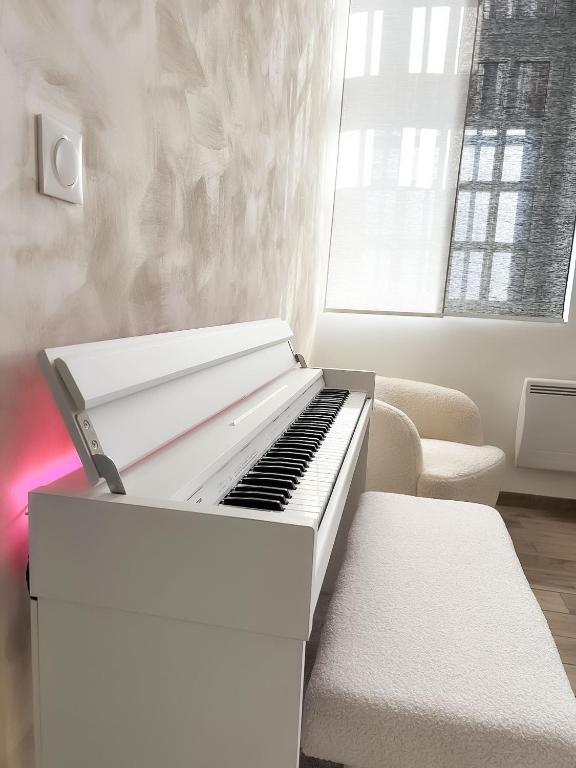 a white piano in a living room with a couch at Le Petit Cocon - Pause douceur in Cambrai