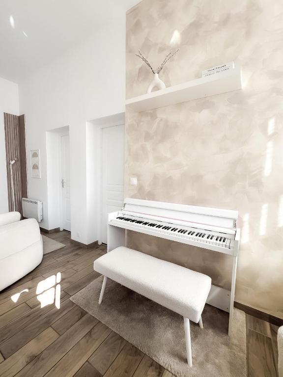 a white piano in a living room with a bench at Le Petit Cocon - Pause douceur in Cambrai