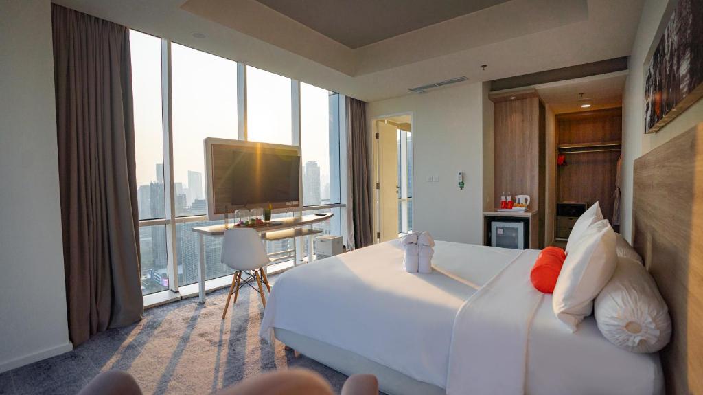 una camera d'albergo con un letto grande e una grande finestra di HARRIS Suites fx Sudirman a Giacarta