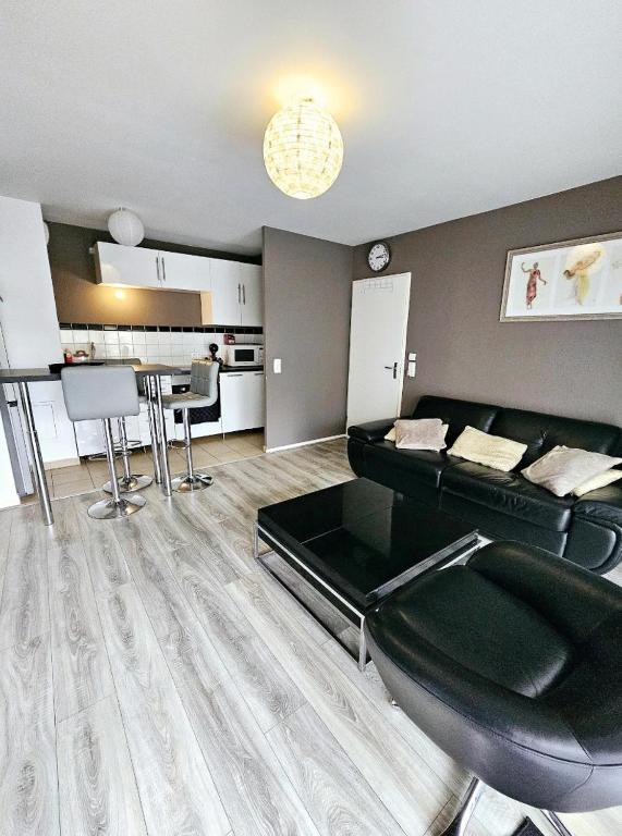 un salon avec un canapé noir et une cuisine dans l'établissement Appartement avec parking privé, à Boussy-Saint-Antoine