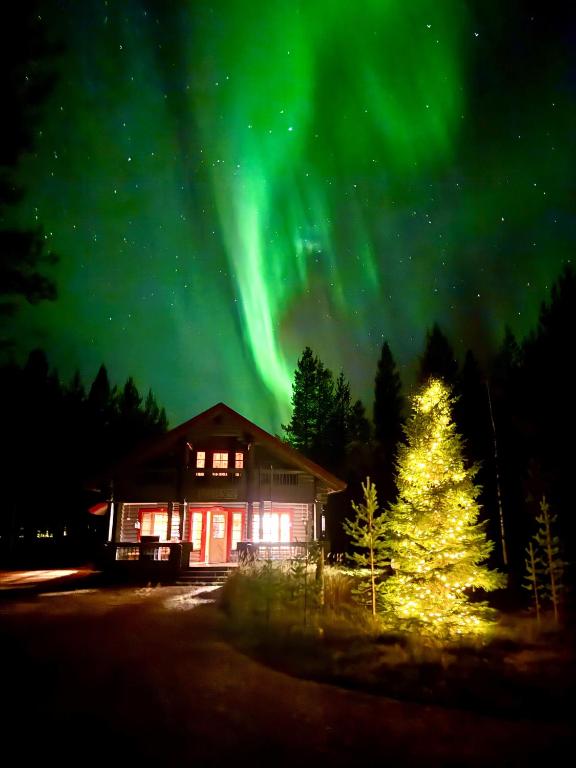 a house with a christmas tree and the aurora at Luoston Väärtin Kammi in Luosto