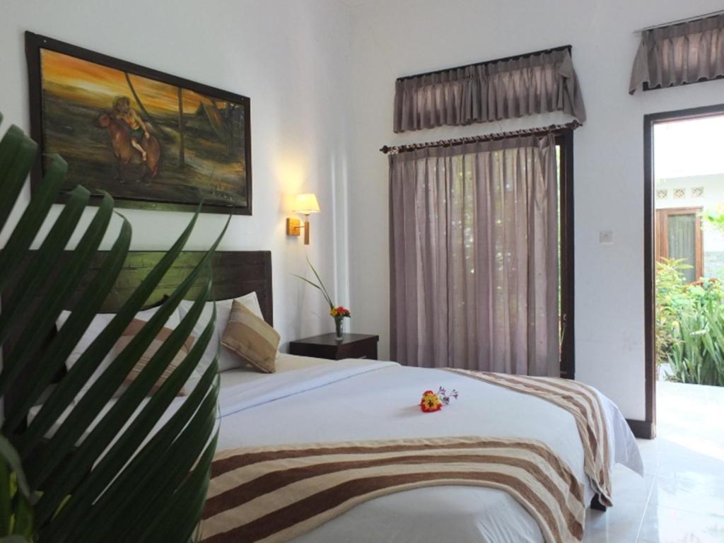a bedroom with a bed and a large window at Ricel Homestay in Gili Trawangan