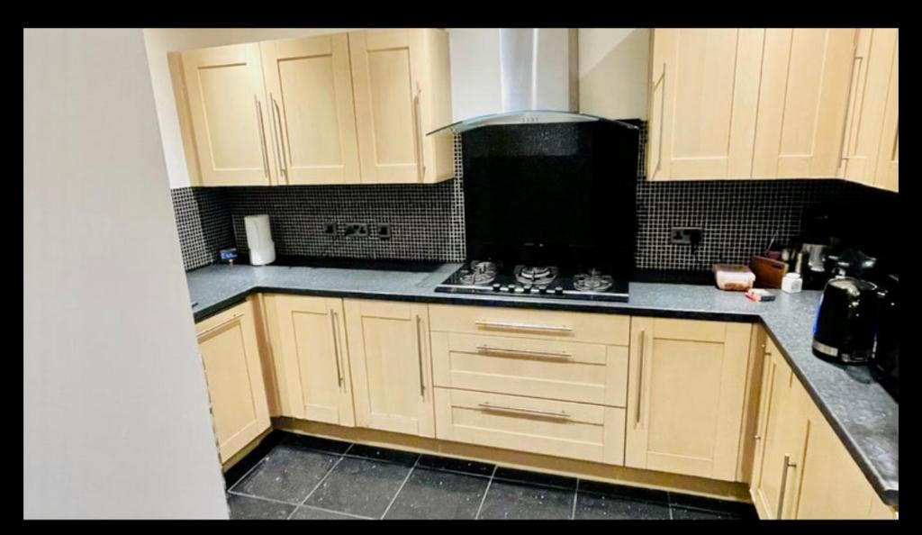 a kitchen with white cabinets and a stove top oven at Wigston Homestay in Wigston Magna