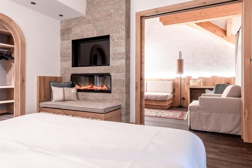 a bedroom with a fireplace and a living room at Renè Dolomites Boutique Hotel in Pozza di Fassa