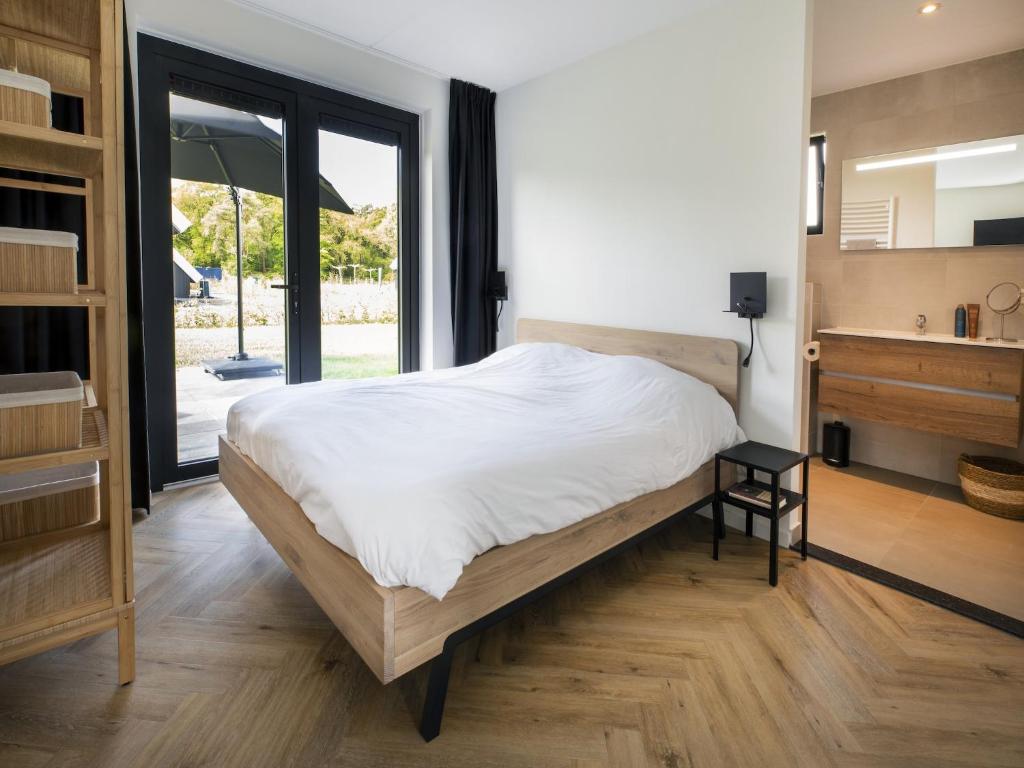 a bedroom with a large bed and a large window at Beautiful villa on the water in Friesland in Sint Nicolaasga