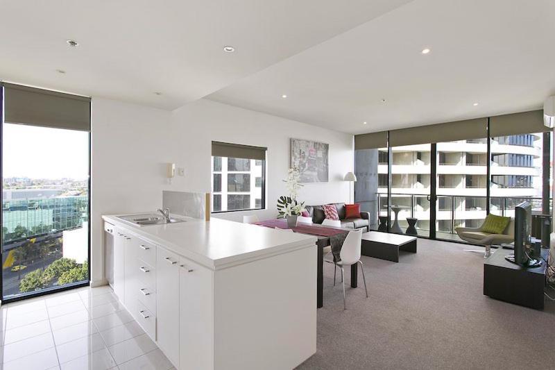 a white kitchen and living room with a view of a building at Docklands Private Collection - NEWQUAY in Melbourne