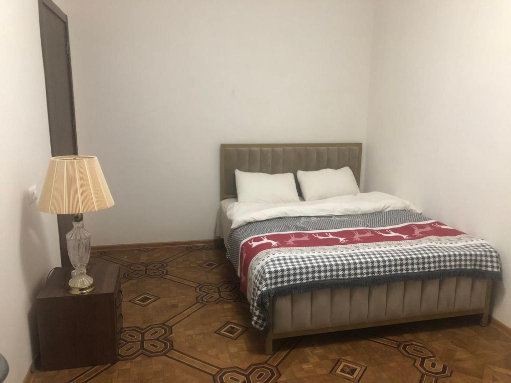 Bett in einem Zimmer mit einer Lampe auf einem Tisch in der Unterkunft Pikrisgora-luxury in Tbilisi City