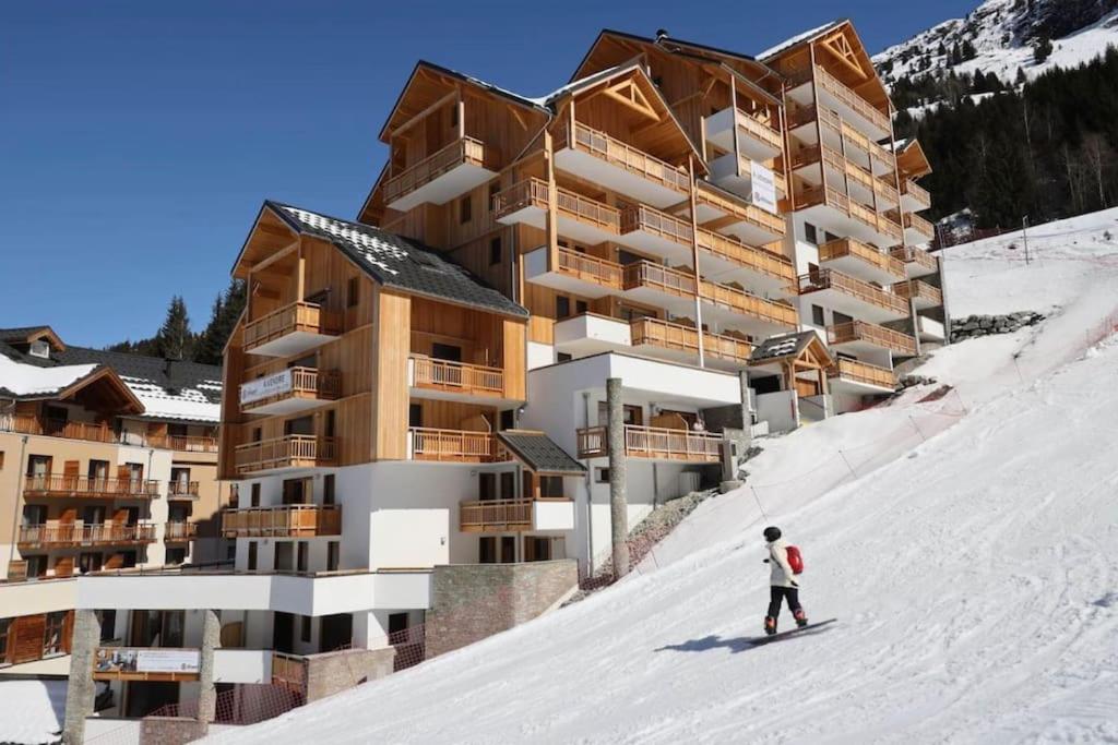 une personne skier sur une piste enneigée devant un bâtiment dans l'établissement Ski in and ski out in Oz, Alpe d'Huez, à Oz