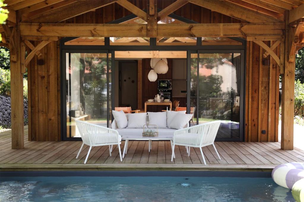 un patio con divano e sedie e una piscina di CLUQUE- Maisons de Vacances a Capbreton