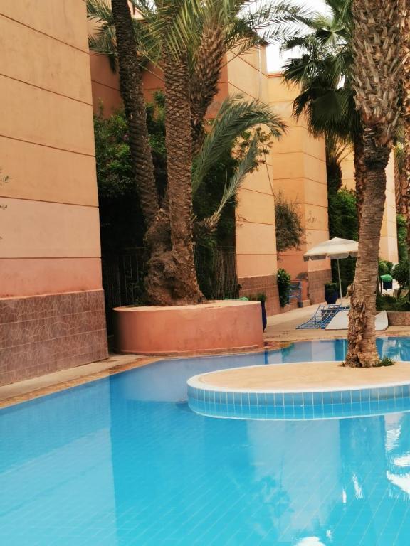 a swimming pool in front of a hotel with palm trees at Riad Dar Fatna in Marrakesh
