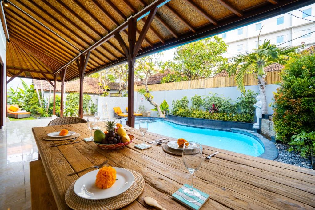 a wooden table with plates of food on it next to a swimming pool at Villa Simara in Seminyak