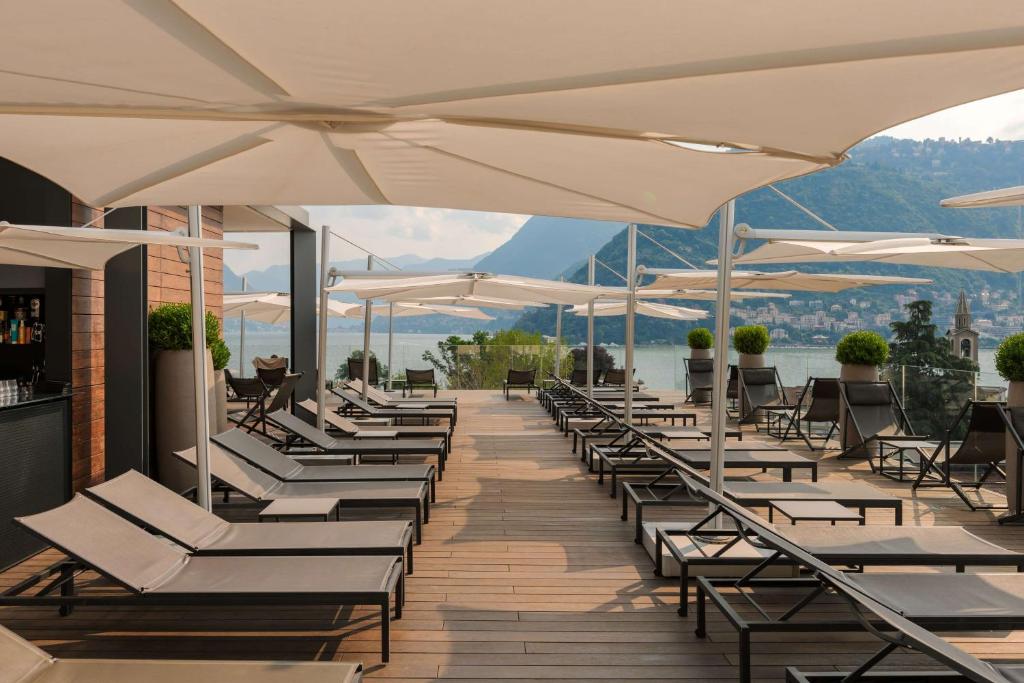 a row of lounge chairs and umbrellas on a deck at Hilton Lake Como in Como