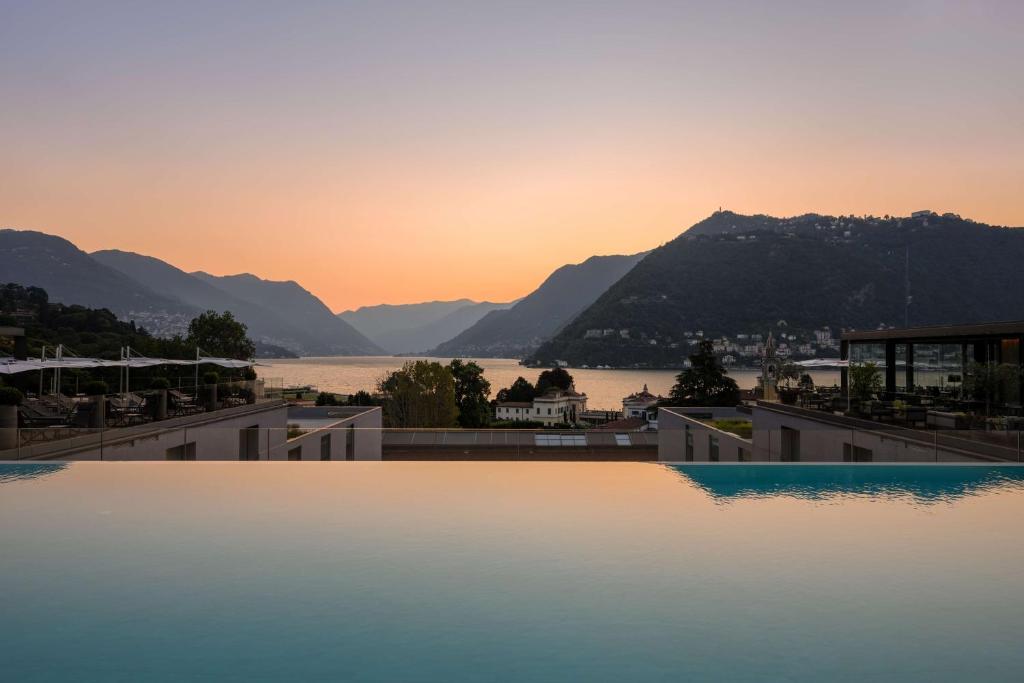 a view of the lake from a hotel swimming pool at sunset at Hilton Lake Como in Como