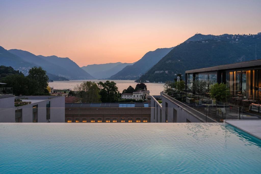 a large swimming pool on a building with a view of the mountains at Hilton Lake Como in Como