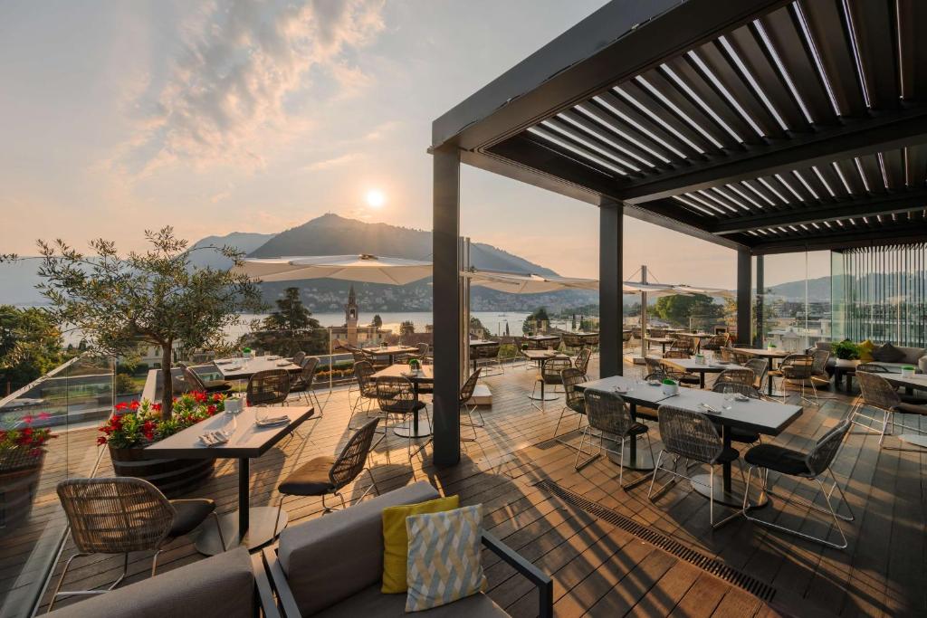 a restaurant with tables and chairs on a deck at Hilton Lake Como in Como