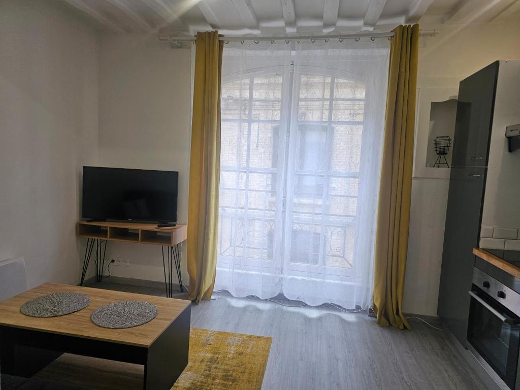 - un salon avec une grande fenêtre et des rideaux jaunes dans l'établissement Chez Camille, à Dieppe