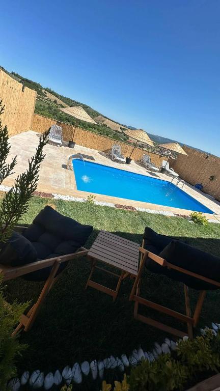 a swimming pool with two loungers and a bench next to at Uysal Dağevleri in Bilecik