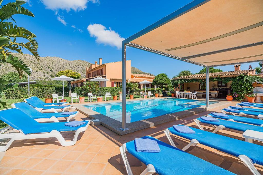 - une piscine avec des chaises longues bleues à côté d'une maison dans l'établissement Villa La Rosaleda - By Dream Villas Pollensa, à El Port