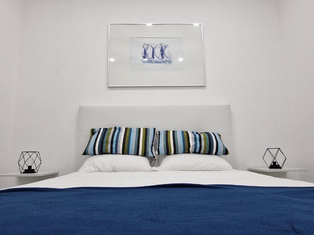 1 dormitorio con 1 cama azul y blanca y 2 almohadas en Marilaura's beach house, en Nazaré