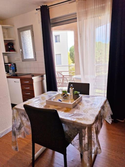 une cuisine avec une table en marbre, des chaises et une fenêtre dans l'établissement Studio cabine pour 4 équipé proche port Cap d'Agde, au Cap d'Agde