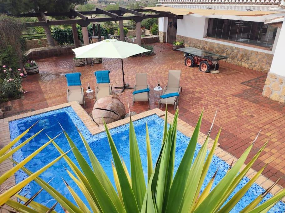 - une piscine avec des chaises, une table et un parasol dans l'établissement Cortijo Bernardino, à Chirivel